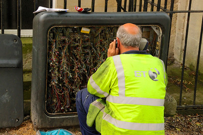 older worker sitting in front of telephone wiring